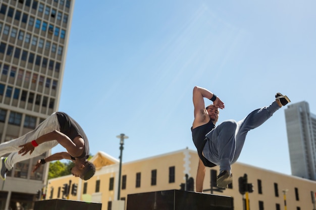 Happy friends doing parkour in the city