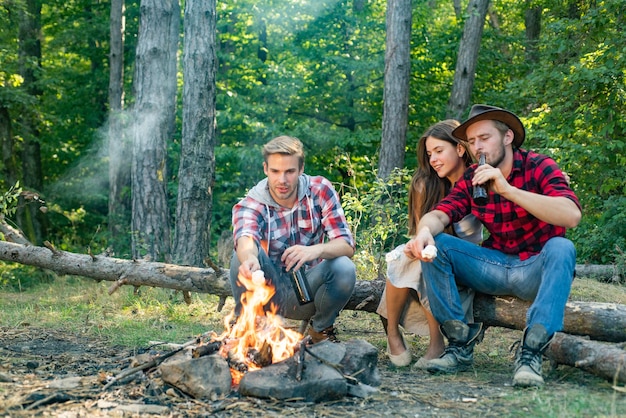 Happy friends enjoying bonfire in nature romantic picnic forest weekend hike friends sit on forest p