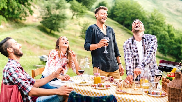 Happy friends group having fun drinking red wine at barbeque pic nic garden party