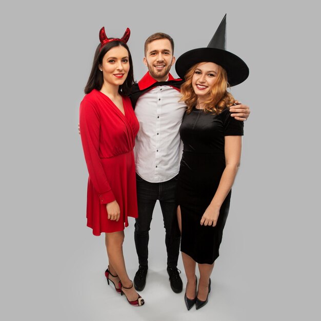 Photo happy friends in halloween costumes over grey