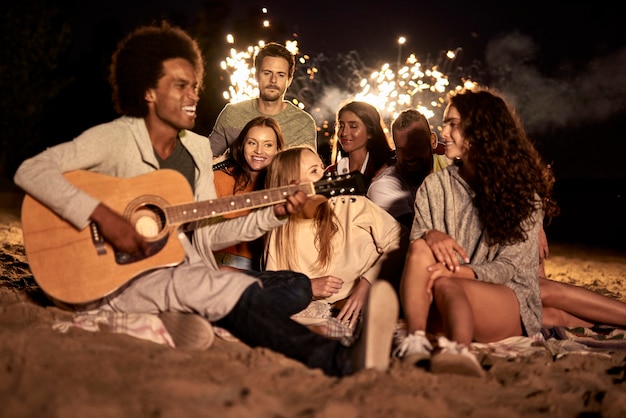 Happy friends having fun on the beach at night