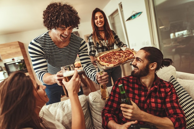 Photo happy friends having fun while eating pizza and drinking beer. they have great weekend in nice company indoors.