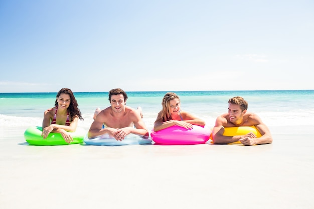 Happy friends lying on inflatable mattress above the water