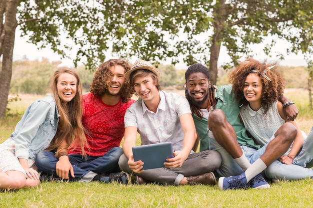 Happy friends in the park looking at tablet