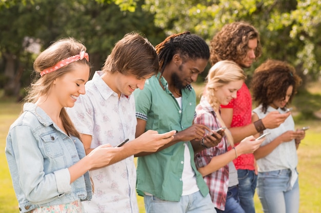 Happy friends in the park using their phones