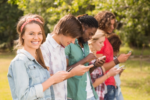 Happy friends in the park using their phones