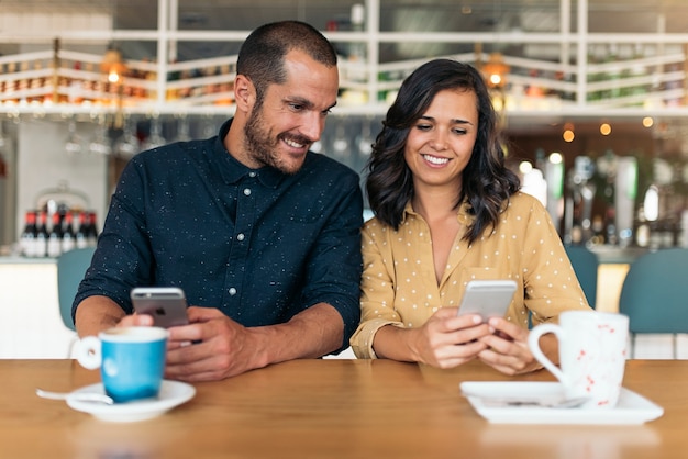 Happy friends using mobile in coffee shop.