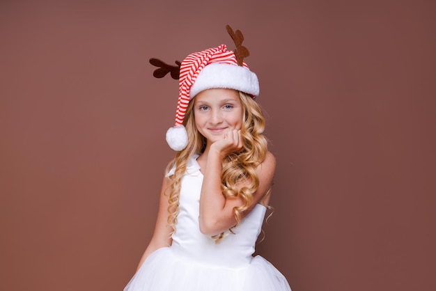 Happy funny child girl in red christmas deer costume smiling looking at camera