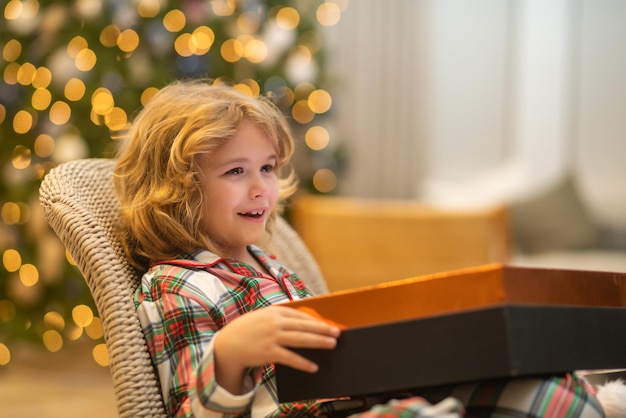 Happy funny child in winter pajama near christmas tree at morning christmas and new year concept