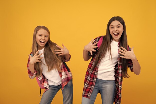 Happy funny teen girls in casual checkered shirt carry backpack school fun