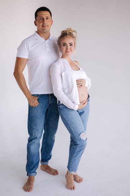 Happy future parents of man and pregnant woman puts hands on belly and waiting for beby movement in