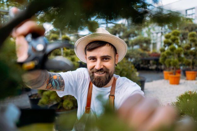 Happy gardener is pruning green bush and looking at camera Gardening tools concept