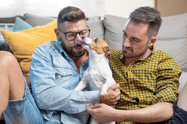 Happy gay couple sitting on floor and playing with dog at home