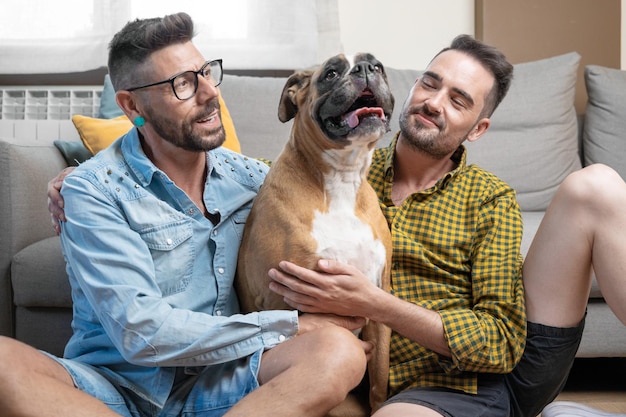 Happy gay couple sitting on floor and playing with dog at home