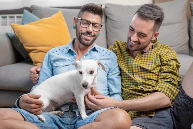 Happy gay couple sitting on floor and playing with dog at home