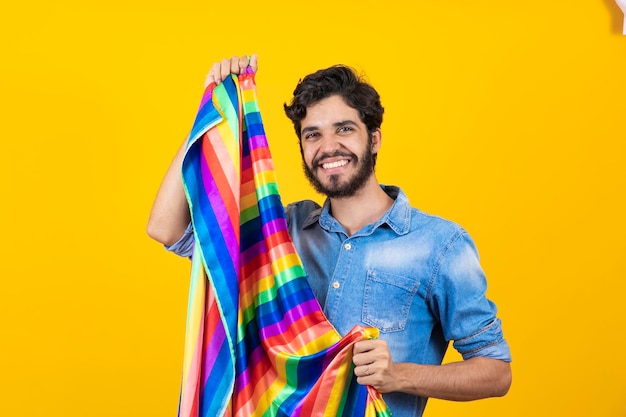 Happy gay man having fun holding rainbow flag symbol of LGBTQ community