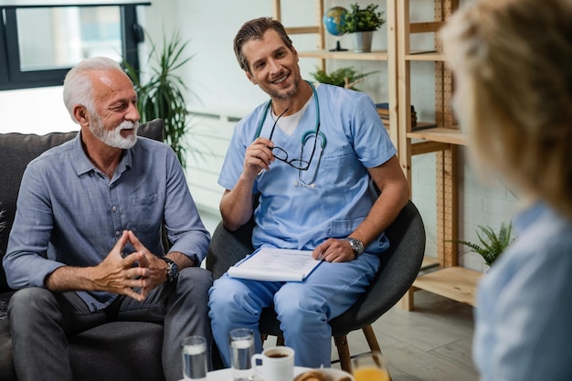 Happy general practitioner communicating with senior patients during a home visit