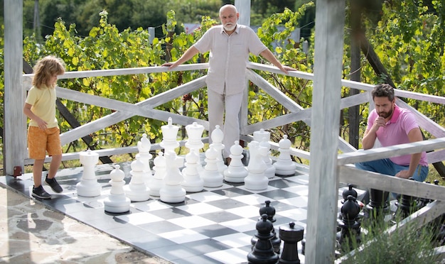 Happy generations of men have fun and playing chess fathers day father and son with grandfather play