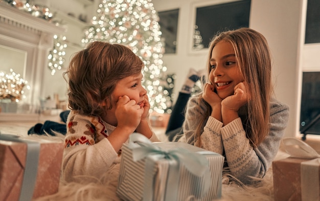 The happy girl and boy with gifts laying on the floor