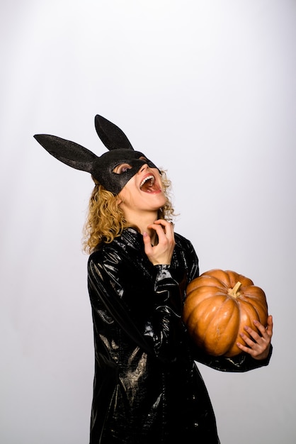 Happy girl in bunny mask with pumpkin woman in black bunny mask sexy girl in halloween party smiling