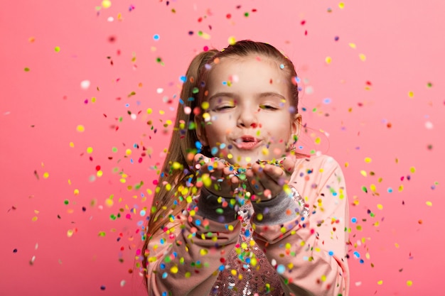 Happy girl celebrating on a pink background. 