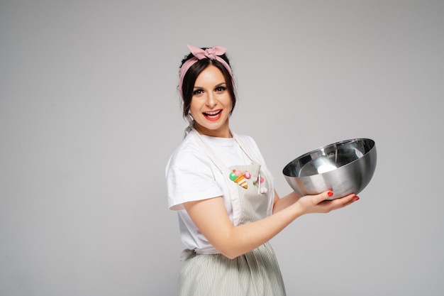 Happy girl cook confectioner in an apron holds a bowl