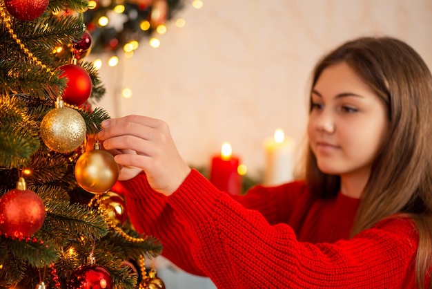 Happy girl decorating christmas tree at home Winter holidays beautiful decoration happy time