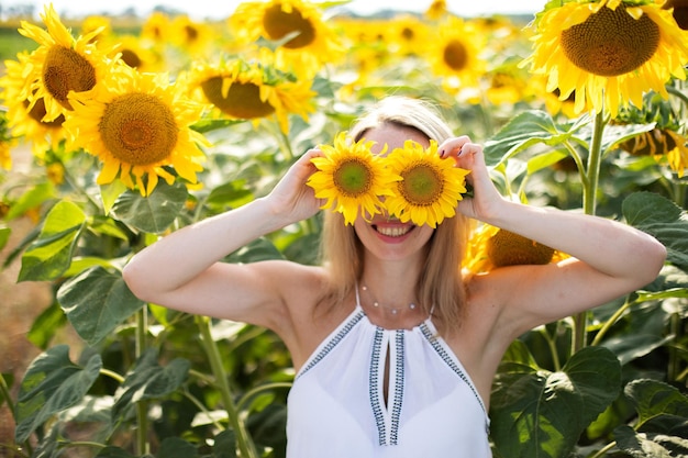 Happy girl enjoys spending time in a field with sunflowers