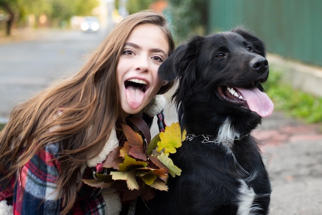 Happy girl gets lovely dog plays and embraces Humans and dogs Girl with tongue embracing puppy dog outdoor