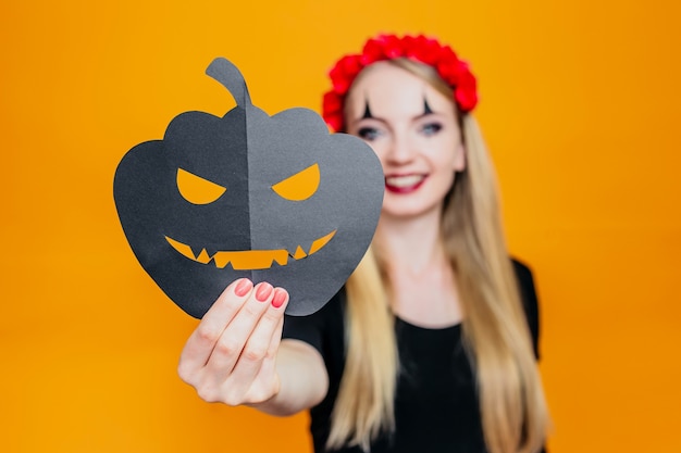 Photo happy girl in halloween costume holding pumpkin and isolated on orange