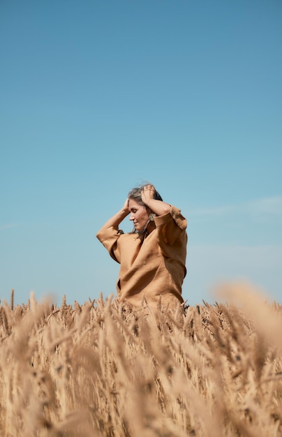 Happy girl in a hat dancing in a field on a clear blue sky background