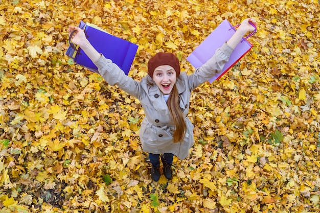 Happy girl in hat holding shopping bags Autumn sales and discounts Top view