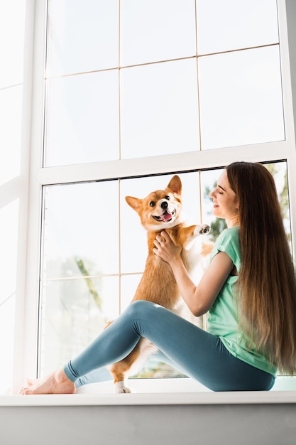 Happy girl hug Corgi dog at home Lifestyle with domestic pet Young woman sitting and play with Welsh Corgi Pembroke