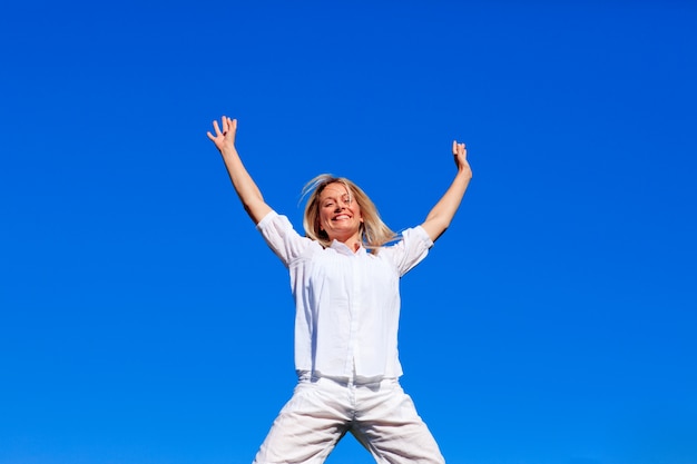 Happy girl jumping against blue sky