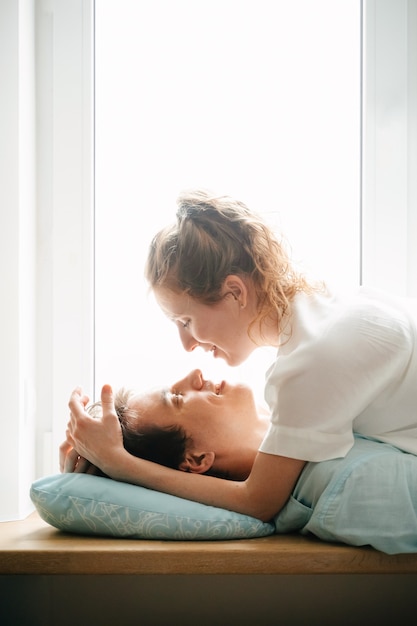 Happy girl and man hugging near window in home. White and blue clothes. Valentine day.