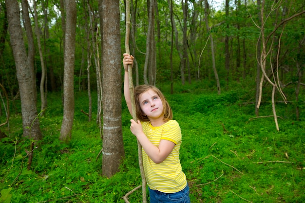 Happy girl playing in forest park jungle with liana