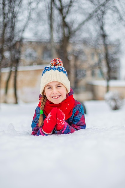 Happy girl playing with snow on a snowy winter walk making snowballs in the park