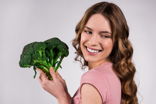 Happy girl posing with broccoli isolated.