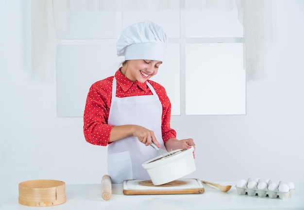 Happy girl prepares dough in kitchen culinary