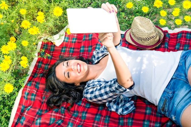 Happy girl reading a tablet among the daisies