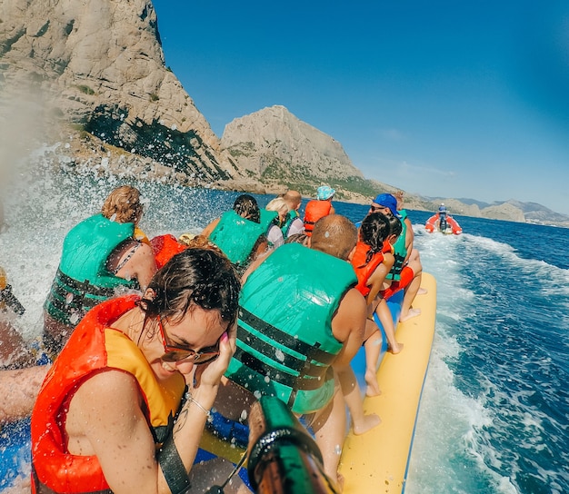 Happy girl rides a banana boat on a vacation on the sea and takes a selfie