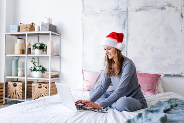 Happy girl in santa hat greets friends merry christmas video chat on laptop