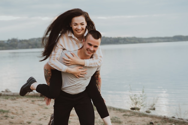 Happy girl on the shoulders of her boyfriend smiling and happy in the summer in nature. The photo is blurry due to movement and short shutter speed