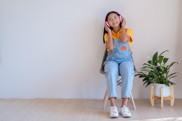 The happy girl sitting on a chair listening to music in minimal room at home