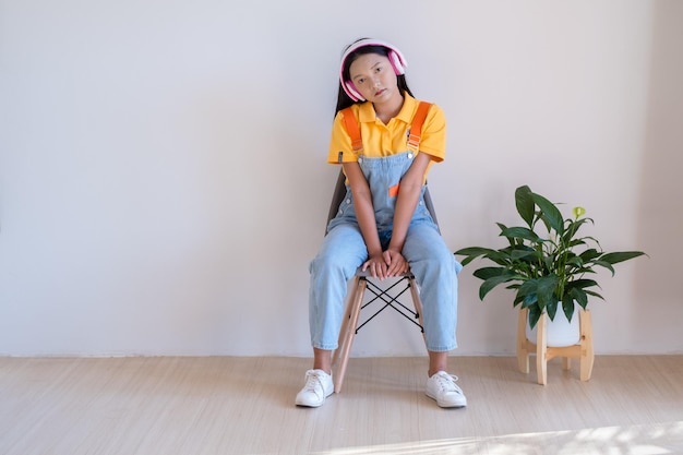 The happy girl sitting on a chair listening to music in minimal room at home