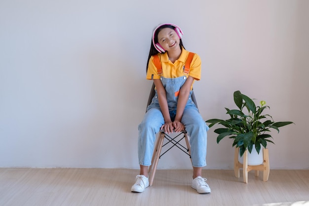 The happy girl sitting on a chair listening to music in minimal room at home