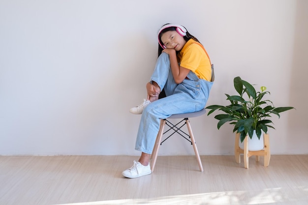 The happy girl sitting on a chair listening to music in minimal room at home