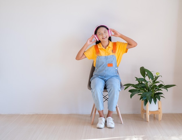 The happy girl sitting on a chair listening to music in minimal room at home