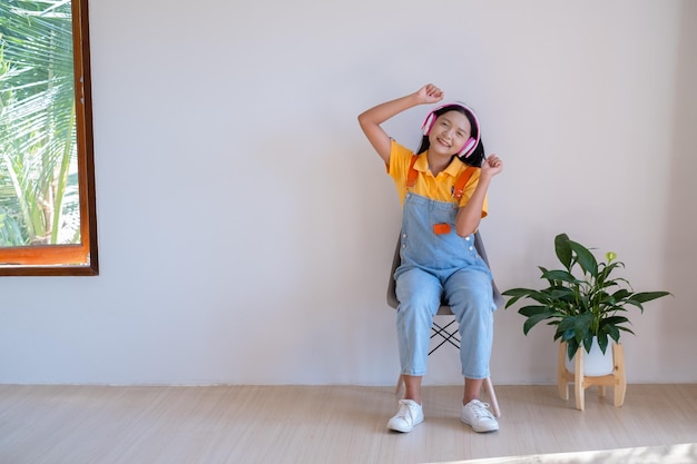 The happy girl sitting on a chair listening to music in minimal room at home