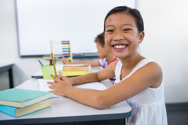 Happy girl studying at desk in in classroom